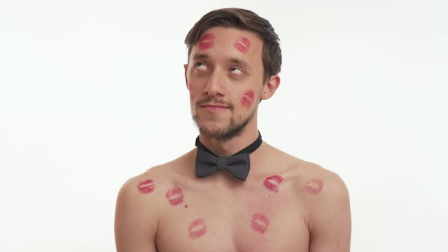 Beautiful sexy half naked man with kiss imprints or marks look at the camera isolated on white wall background. Nice guy with gray bow tie flirt, swing. Romantic concept of Valentine's day close up. 