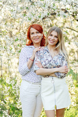 Two women, one young and the other older, in the spring in a beautiful garden with white flowers. Photo from the waist up