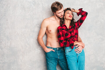 Hot beautiful woman and her handsome boyfriend. Models posing near gray wall in jeans clothes. Young passionate couple hugging before having sex. Sensual pair getting closer for kiss. Lover couple