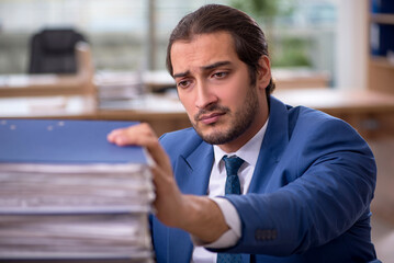 Naklejka premium Young male employee unhappy with excessive work in the office