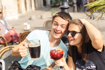 young beautiful couple travelers are sitting at a table in a cafe in the old city of Europe at sunset