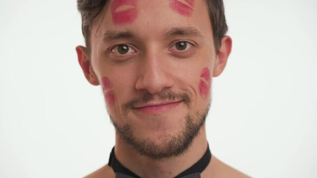 Close-up portrait of young beautiful smiling European Casanova man 20s with brown hair, kiss imprints having beard and mustache looking at camera. Handsome guy isolated over white background indoor.
