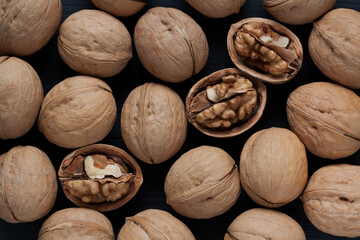 whole and split walnuts lie on a black background