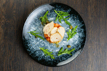 salmon tartare with pepper and tomatoes. fish tartare with thin slices of white bread on a blue plate. view from above