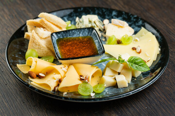 cheese plate with green grapes, crunchy croutons and nuts. set of different types of cheese with honey on a marble plate