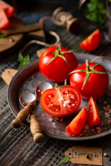 Ripe juicy tomatoes on metal plate on rustic wooden table