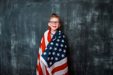 Back to school. Little patriotic boy kid covered on united states of america flag on independence day with a confident expression on smart face thinking serious