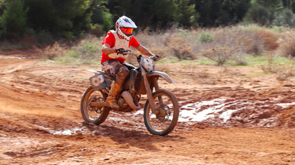 Professional dirt bike motocross rider performing stunts in extreme mud terrain track