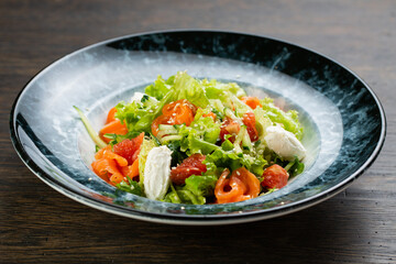 Greek salad of tomatoes, pickled peppers, cucumbers, lettuce and feta cheese. greek salad with olives and white sesame seeds on a blue marble plate