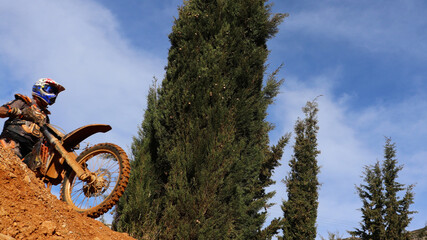 Professional dirt bike motocross rider performing stunts and flying from jump in extreme terrain track
