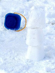 three snow prisms stand on top of each other isolated on white snow background with blue plastic square bucket