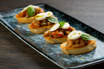 vegetable bruschetta with egg and cheese on white toasted bread. bruschetta on a blue plate
