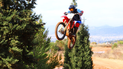 Professional dirt bike motocross rider performing stunts and flying from jump in extreme terrain...