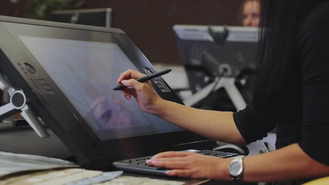 The designer draws on a graphics tablet. Working with interactive pen display. Drawing on a graphics tablet. closeup. Wallpaper production.