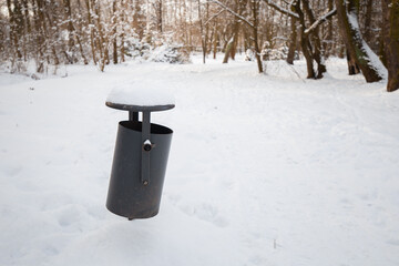 Bin on the street in winter in the snow. Trash can covered with snow are in winter park
