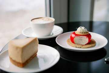 Sliced ​​mousse cake and a slice of classic New York-style cheesecake.Red desserts on a plate in a cafe. Composition of a sweet snack in a cafe. Aromatic cappuccino coffee.