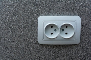 An electrical outlet on a gray, textured wall. Image for project and design. The concept of electrification, repair of electrical equipment.