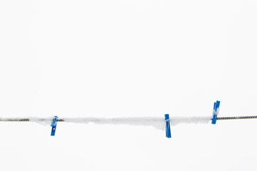 winter background: clothesline covered with snow, several blue clothespins, selective focus
