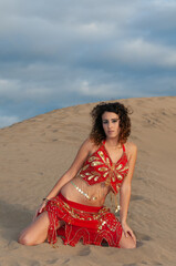 Arab belly dancer in the desert at sunset