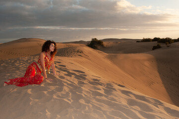 Arab belly dancer in the desert at sunset