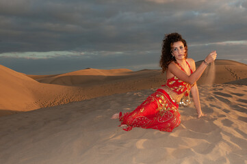 Arab belly dancer in the desert at sunset