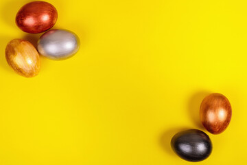 Multi-colored eggs on a uniform yellow background with place for text.