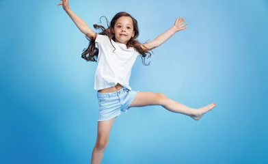 Foto op Aluminium Cheerful child jumping in a blue room © konradbak