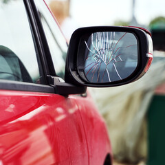 Red car with broken side door mirror parked on the street