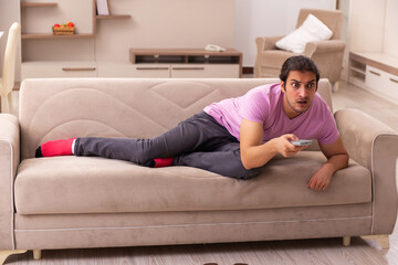 Young man watching tv at home during pandemic