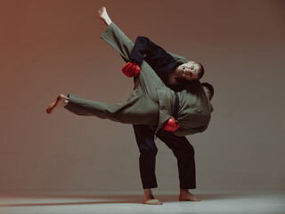 Sparring of two fighting males in kimono and boxing gloves during battle, knockout, martial arts, mixed fight concept