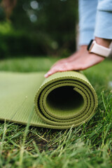 Close-up of woman folding roll fitness after working out in the park