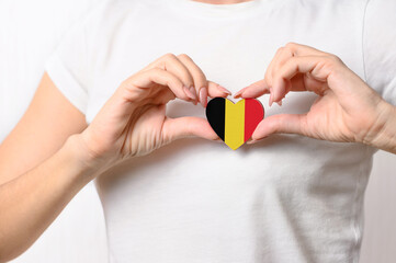Love Belgium. The girl holds a heart in the form of the flag of Belgium on her chest. Belgian patriotism concept