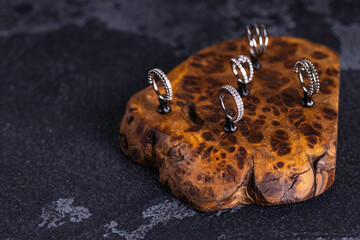 Beautiful piercing jewelry on wooden display. Macro shot. Selective focus.
