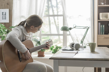 Young woman playing guitar at home