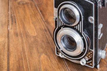 detail of the lenses of an antique twin lens reflex camera, on a wooden table, antique and classic photography, copy space, horizontal