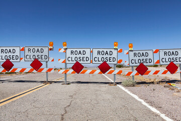 Highway road closed signs and barricades near Route 66 in the California Mojave Desert.