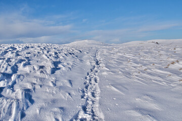 Path in snow leading to the peak of a snow covered mountain in winter