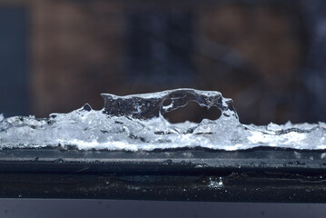 Transparent ice on the window pane of the window frame.