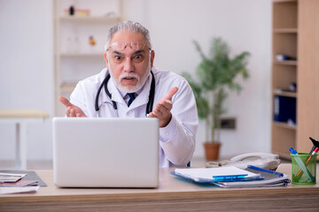 Old male doctor in telemedicine concept