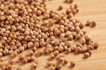 Heap of dry coriander seeds on a wooden background. Close up view.