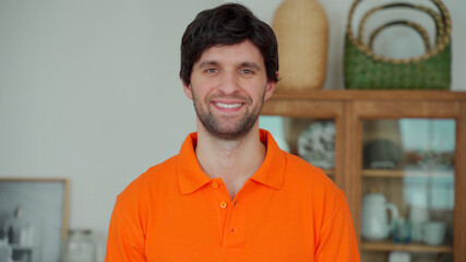 Portrait of a happy man in a orange shirt looking at the camera and smiling