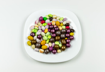 Colorful lollipops on a plate and colorful round candies. Top view white background. Close-up