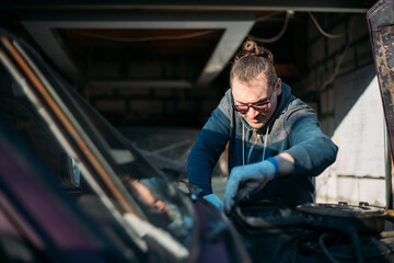 Fototapeta na wymiar A man repairs a car, opens the hood