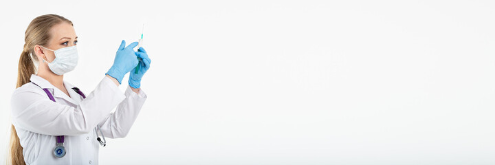 Young nurse in a mask dials the vaccine into a syringe while sitting in a hospital next to a patient. Female patient waiting for flu injection. Concept of vaccination and protection against influenza