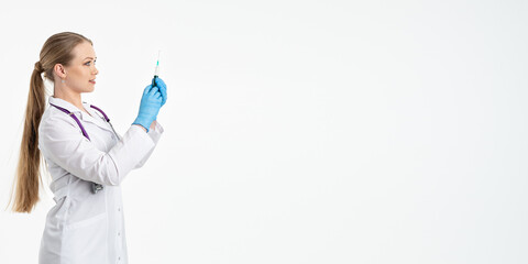 A young nurse in a mask and white coat holds a syringe with a needle for injections, flu shots, covid. The concept of vaccination and protection against influenza, from a pandemic. copy space. banner
