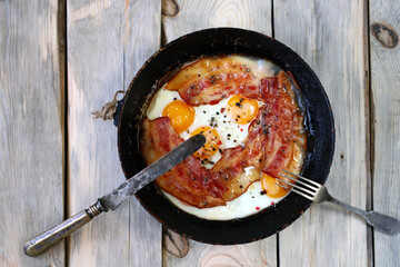 Scrambled eggs with bacon in a frying pan. Traditional delicious breakfast. Juicy appetizing scrambled eggs with bacon.