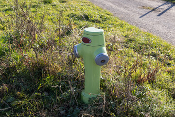 green-yellow neon colored fire hydrant on a meadow, in the daytime without people, hydrants save lives in a fire of buildings