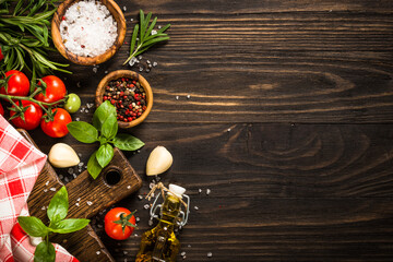 Food cooking background with cutting board, spices, herbs and vegetables at wooden table. Ingredients for cooking. Top view with copy space.