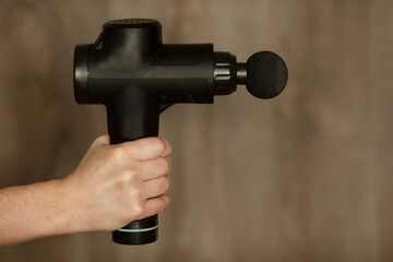 Hand holding a therapeutic percussive massage gun.