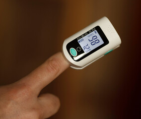 Pulse oximeter on finger showing oxygen saturation and heart rate. Oxymeter.